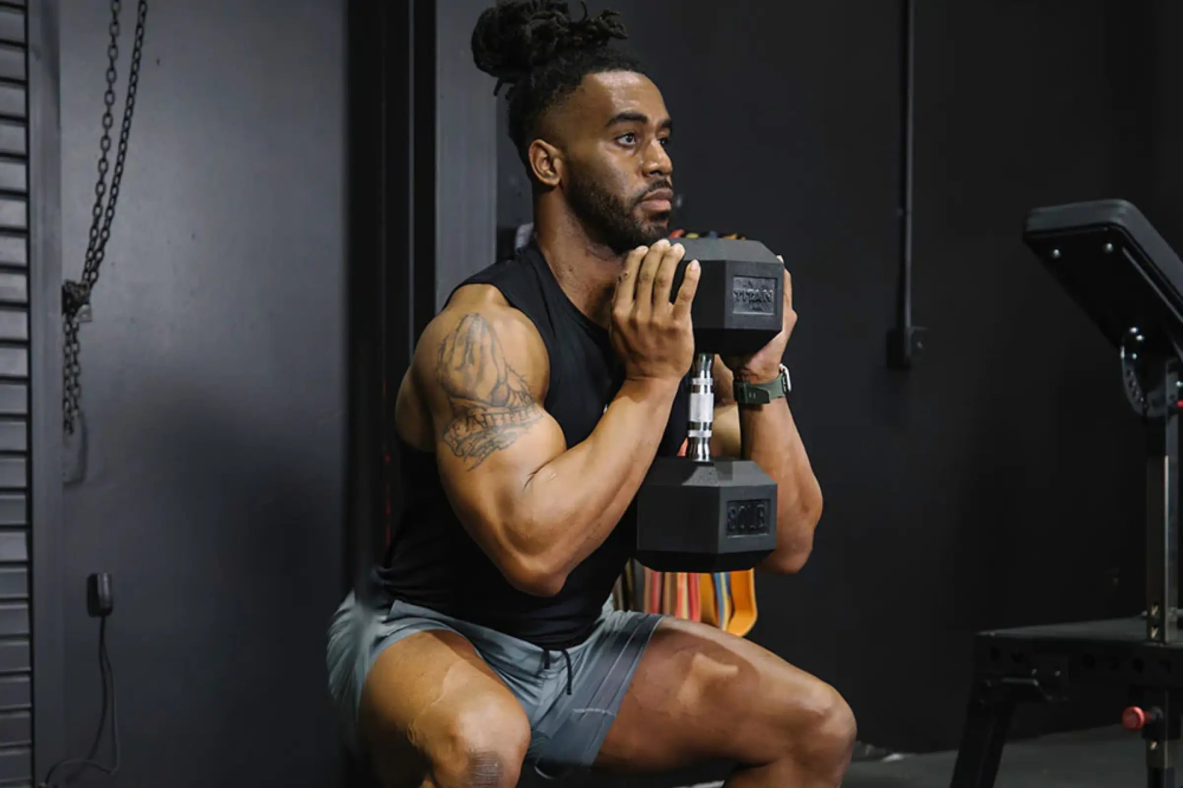 Man performing a goblet squat with a Titan Fitness rubber hex dumbbell in a home gym.